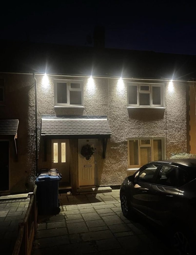 House front lit at night by soffit downlights